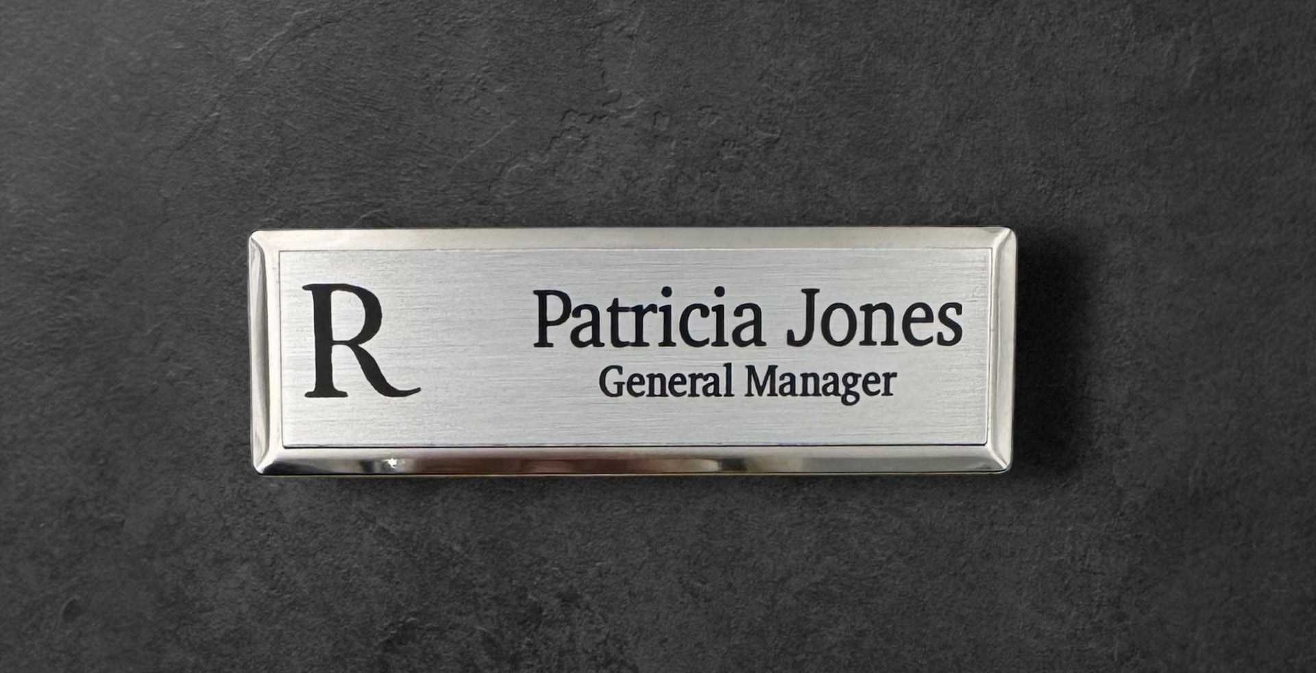 Silver metal beveled name tag with a brushed silver metal face, with logo, name and title